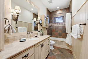 Bathroom with vanity, shower / tub combo, and stone tile floors