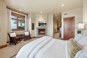 Carpeted bedroom featuring recessed lighting and a warm lit fireplace