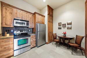 Kitchen with appliances with stainless steel finishes, tasteful backsplash, brown cabinetry, and recessed lighting
