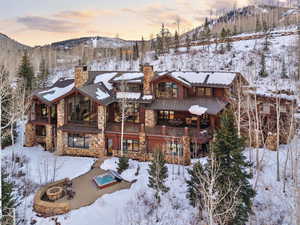 View of front of home with stone siding, a chimney, a balcony, and a mountain view