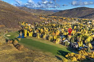 Aerial view of property and surrounding area with a mountain backdrop and a golf course