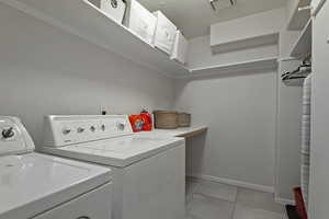Laundry area with washer and clothes dryer, light tile patterned floors, and a textured ceiling