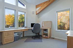 Office featuring light carpet, built in study area, and vaulted ceiling