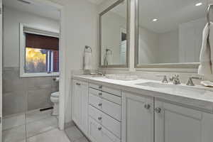 Full bath featuring double vanity, light tile patterned floors, tile walls, and recessed lighting