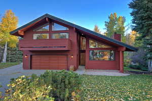 View of front of house with a chimney, an attached garage, driveway, and a front lawn