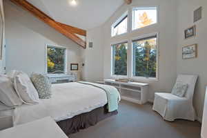Carpeted bedroom featuring beamed ceiling and high vaulted ceiling