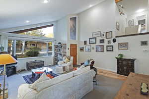 Living room with high vaulted ceiling, wood finished floors, and recessed lighting
