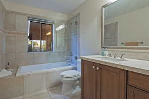 Bathroom featuring vanity, tiled shower / bath combo, and light tile patterned flooring