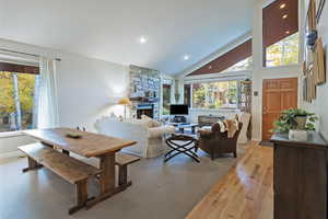 Dining space featuring high vaulted ceiling, light wood-style flooring, a fireplace, and recessed lighting