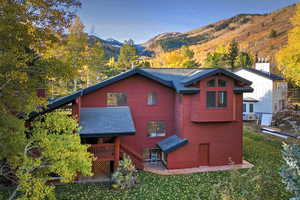 Rear view of property with a mountain view, a yard, and a shingled roof