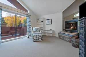 Sitting room with vaulted ceiling, a glass covered fireplace, and carpet