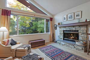 Living room with lofted ceiling, a fireplace, and wood finished floors