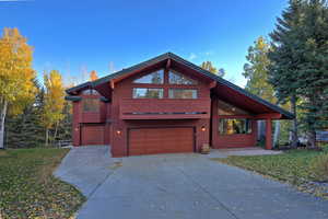 Rustic home featuring a garage, driveway, and a front yard