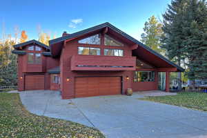 View of front of house featuring a chimney, driveway, a garage, and a front lawn