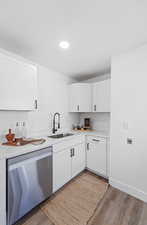 Kitchen featuring dishwasher, white cabinets, light wood-style flooring, recessed lighting, and light stone counters
