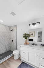 Full bath with vanity, a shower stall, and light wood finished floors