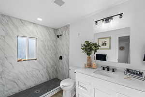 Bathroom featuring a marble finish shower, vanity, and recessed lighting