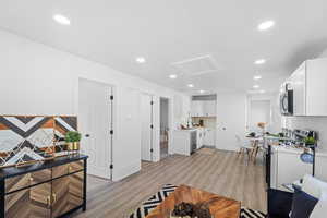 Living room with attic access, light wood-type flooring, and recessed lighting