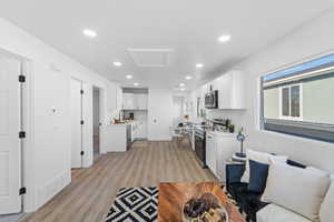 Kitchen with light countertops, white cabinetry, stainless steel appliances, light wood-style flooring, and recessed lighting