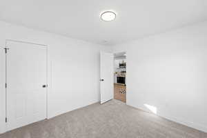 Unfurnished bedroom with light carpet and baseboards