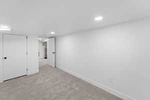 Finished below grade area with light colored carpet and recessed lighting