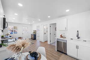 Kitchen featuring white cabinetry, recessed lighting, stainless steel dishwasher, light stone countertops, and light wood finished floors