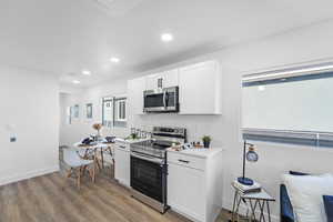 Kitchen with stainless steel appliances, white cabinetry, light wood-style flooring, and recessed lighting