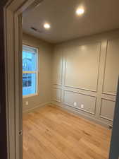 Unfurnished room with recessed lighting, light wood-style floors, and a decorative wall