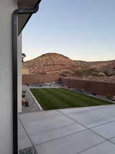 Yard at dusk featuring a fenced backyard, a patio, and a mountain view