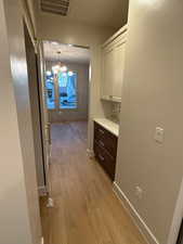 Hallway with light wood finished floors and a chandelier