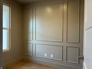 Unfurnished room with light wood-style floors and a decorative wall