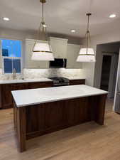 Kitchen featuring stainless steel appliances, light wood-type flooring, recessed lighting, pendant lighting, and a center island