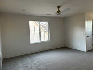Carpeted spare room featuring a ceiling fan and baseboards