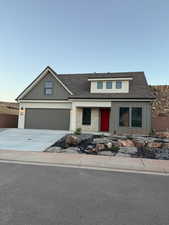 View of front facade with board and batten siding, driveway, a shingled roof, covered porch, and an attached garage