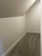 Bonus room with lofted ceiling and dark colored carpet