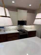 Kitchen featuring recessed lighting, appliances with stainless steel finishes, white cabinets, and decorative backsplash