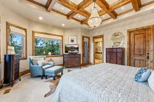 Carpeted bedroom featuring coffered ceiling, a chandelier, and beam ceiling