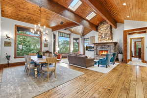 Dining space with a fireplace, healthy amount of natural light, hardwood / wood-style flooring, a wooden ceiling with exposed beams, and a skylight