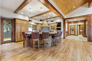 Kitchen with hanging light fixtures, light stone countertops, a kitchen breakfast bar, glass insert cabinets, and a large island