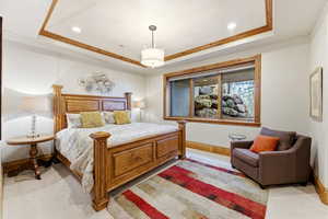 Bedroom featuring a tray ceiling, recessed lighting, ornamental molding, and light carpet