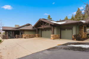 Craftsman house featuring stone siding, concrete driveway, an attached garage, and a chimney