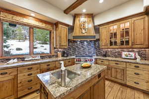 Kitchen featuring premium stove, light wood-type flooring, premium range hood, recessed lighting, and brown cabinetry