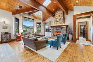 Living room featuring light wood-style floors, a skylight, wooden ceiling, a fireplace, and recessed lighting