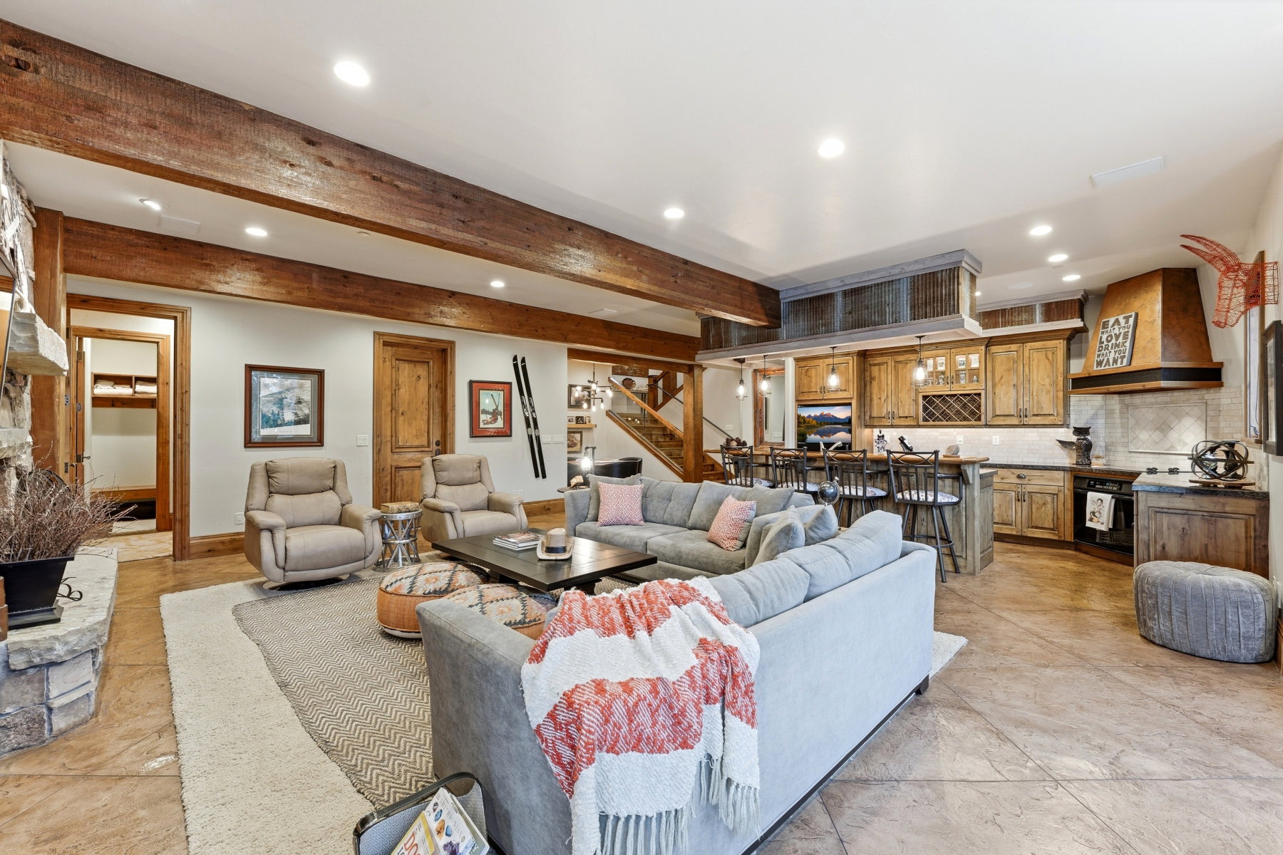 Living room with beamed ceiling, stairs, recessed lighting, and a stone fireplace