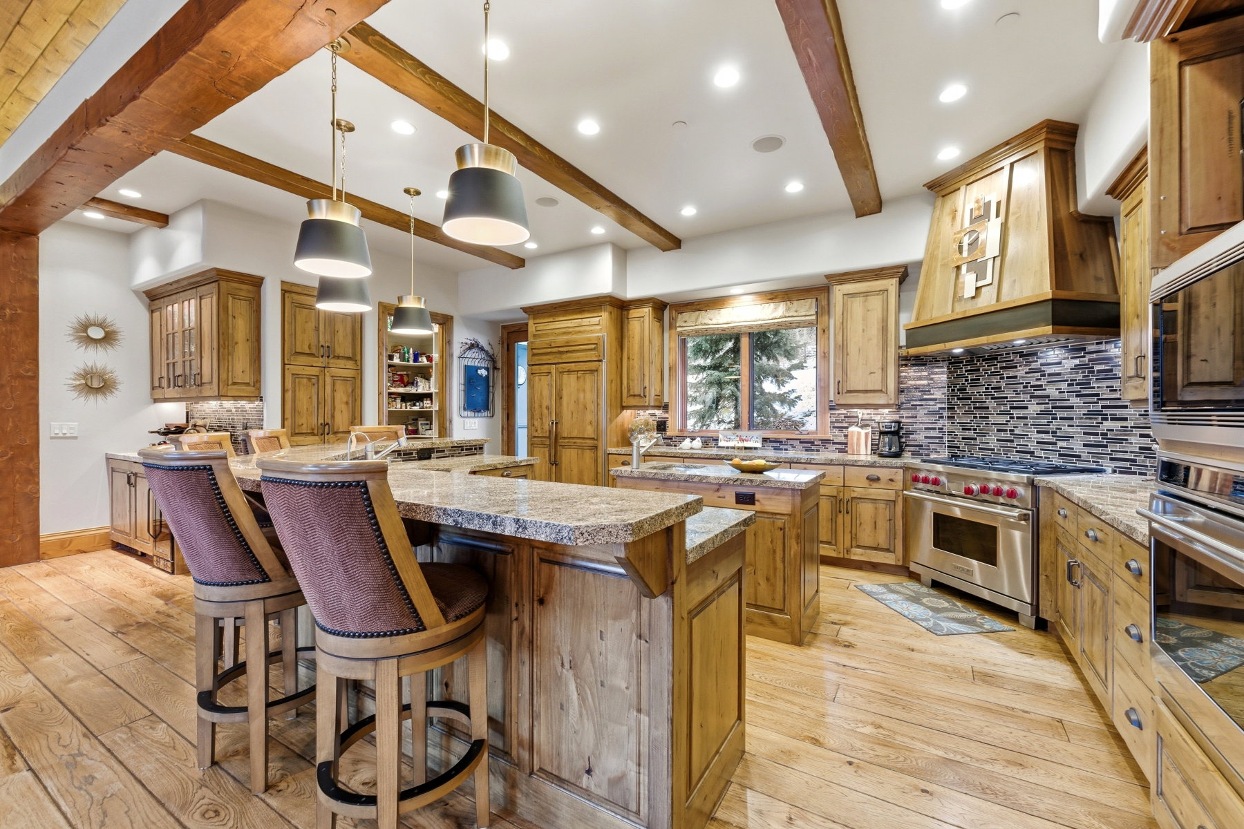 Kitchen with backsplash, glass insert cabinets, decorative light fixtures, a kitchen breakfast bar, and light wood-style floors