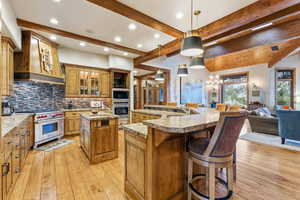 Kitchen with glass insert cabinets, hanging light fixtures, brown cabinets, a chandelier, and a kitchen bar