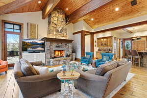 Living area with light wood finished floors, a wooden ceiling with exposed beams, a fireplace, high vaulted ceiling, and recessed lighting