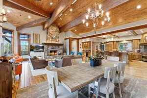 Dining space with a fireplace, a chandelier, a wooden ceiling with exposed beams, light wood-style flooring, and recessed lighting