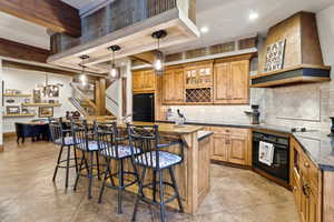 Kitchen featuring black appliances, glass insert cabinets, a kitchen breakfast bar, a kitchen island, and premium range hood