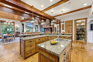 Kitchen with brown cabinetry, decorative light fixtures, light wood-style floors, beam ceiling, and recessed lighting